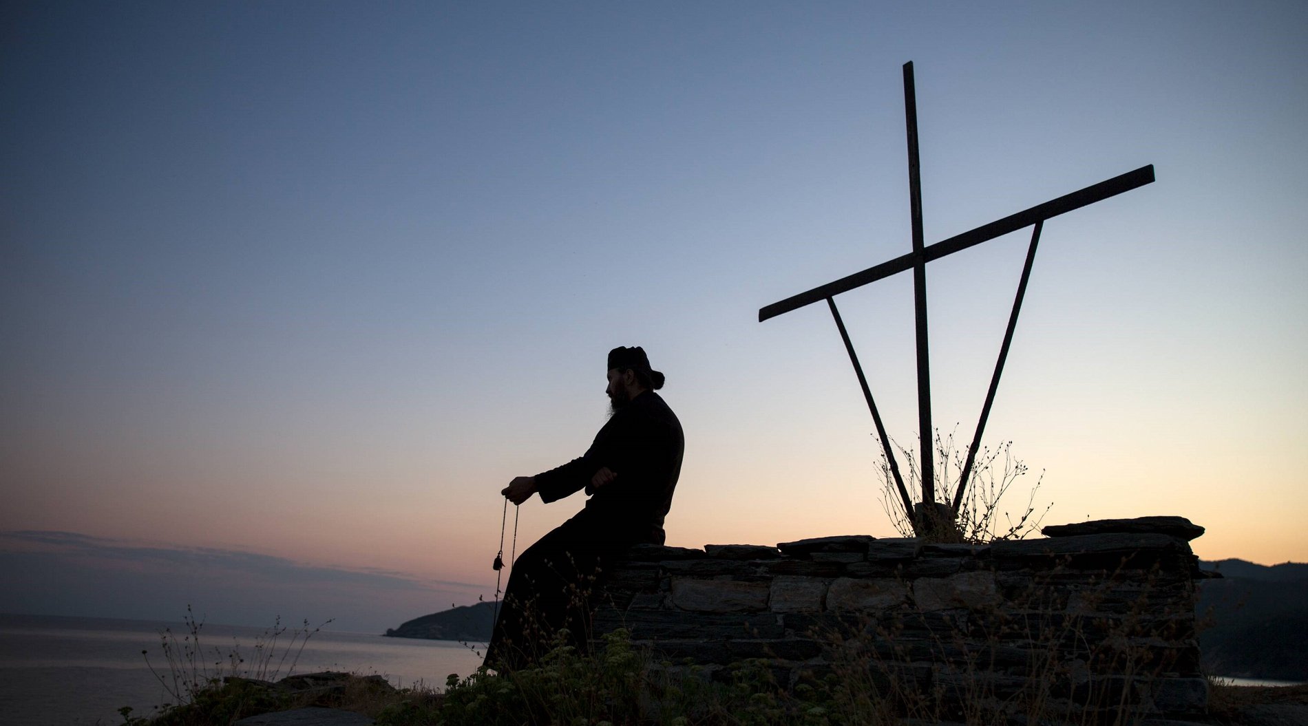 A monk is praying on Mount Athos as the sun rises.